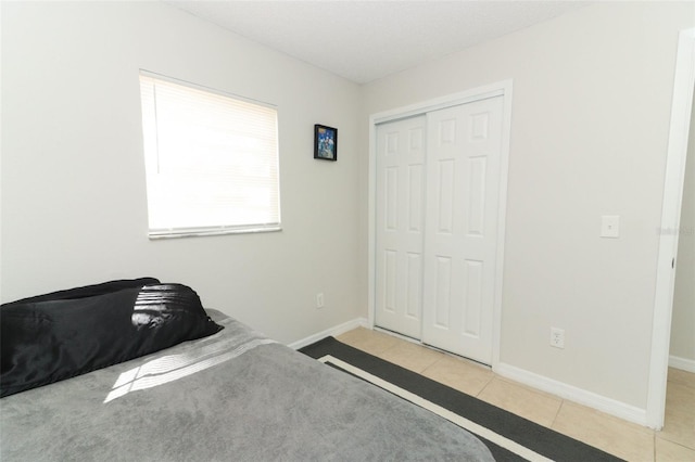 unfurnished bedroom with a closet, baseboards, and tile patterned floors