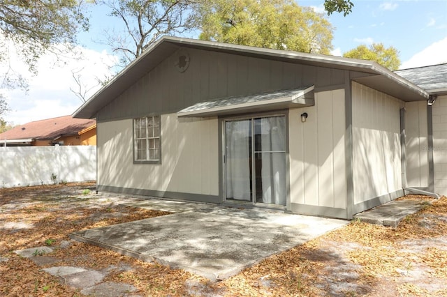 rear view of house with a shingled roof, fence, and a patio