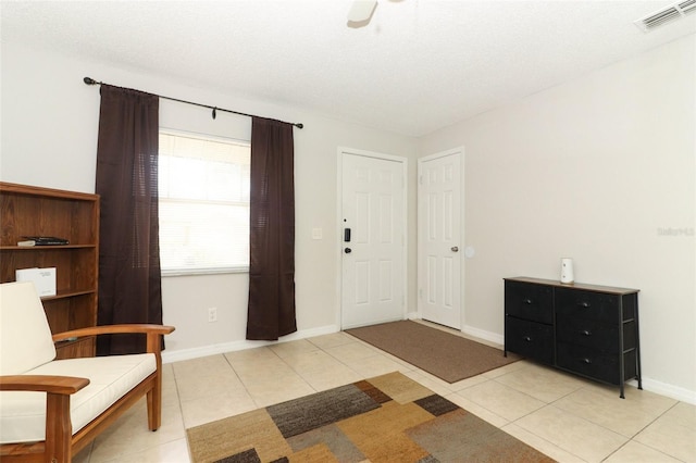 interior space with visible vents, light tile patterned flooring, ceiling fan, a textured ceiling, and baseboards