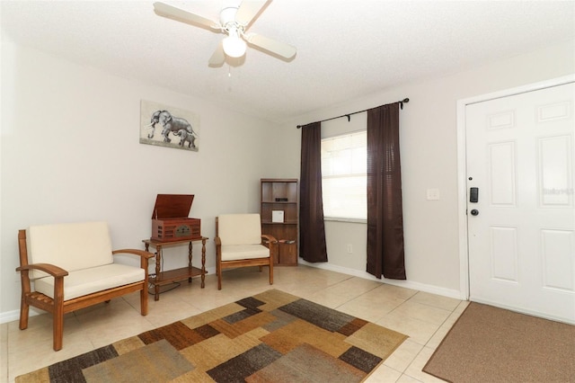 living area with ceiling fan, baseboards, and light tile patterned floors