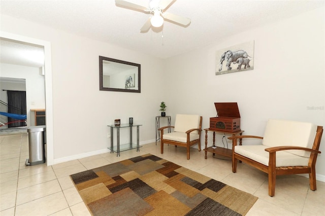 living area with light tile patterned floors, a ceiling fan, and baseboards