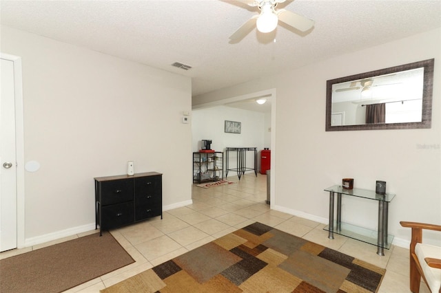 spare room with light tile patterned floors, baseboards, visible vents, and a textured ceiling