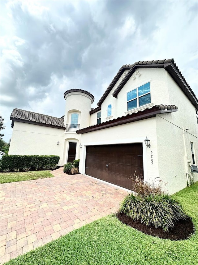 mediterranean / spanish home with stucco siding, decorative driveway, and a garage