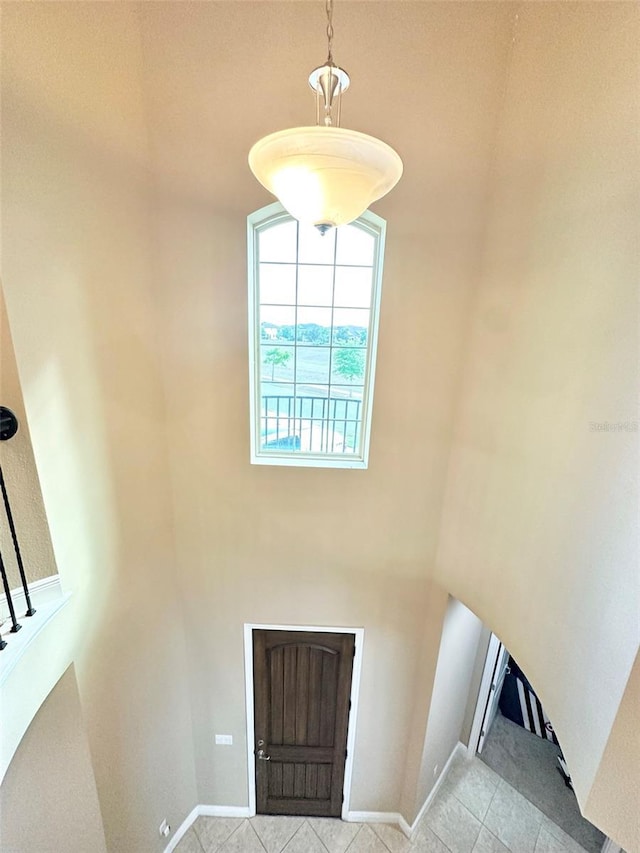 entrance foyer with light tile patterned floors, stairway, baseboards, and a towering ceiling