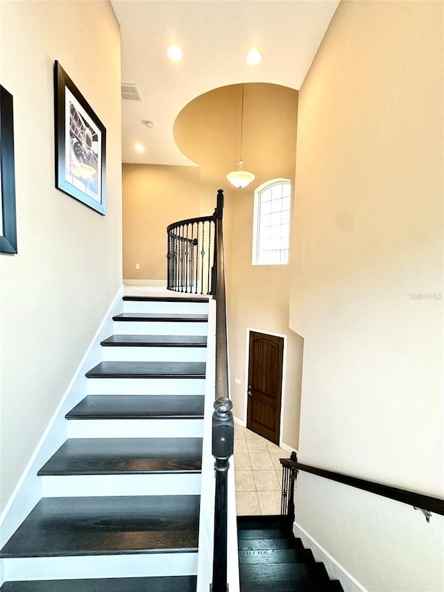 stairway with visible vents, a high ceiling, recessed lighting, and baseboards