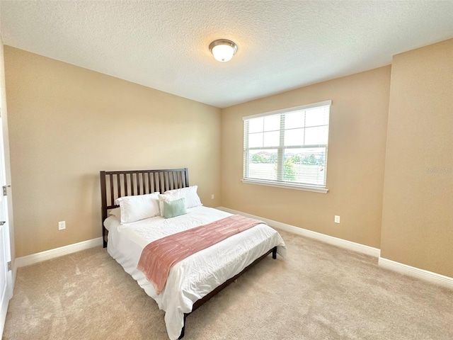 bedroom featuring carpet, baseboards, and a textured ceiling