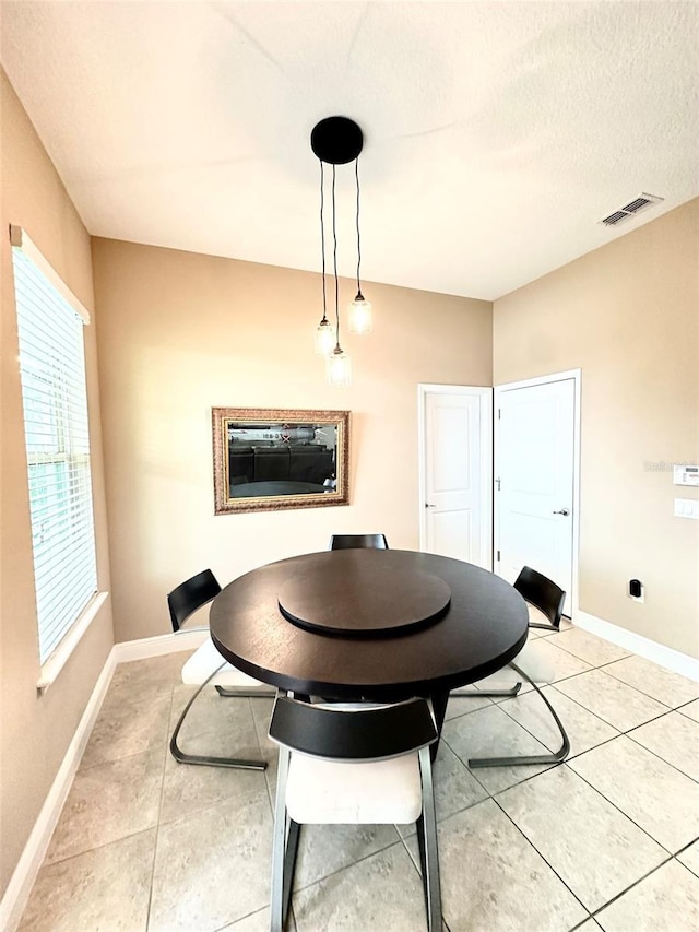 dining room featuring light tile patterned floors, visible vents, baseboards, and a textured ceiling