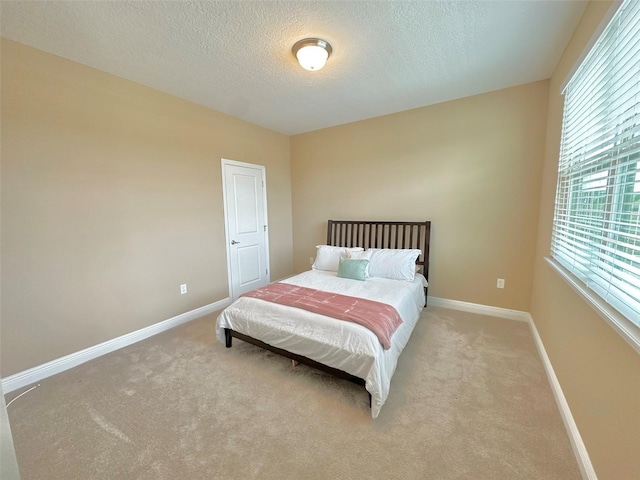 bedroom with light colored carpet, a textured ceiling, and baseboards