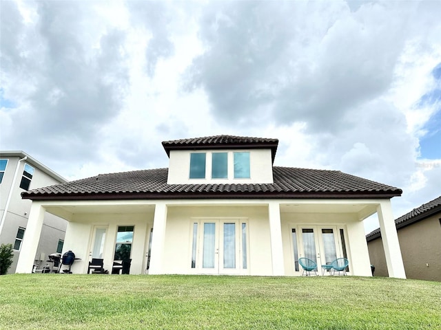 back of house with a tiled roof, stucco siding, french doors, and a yard