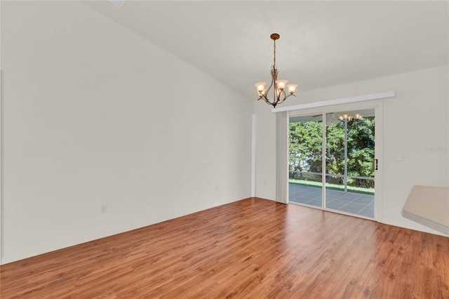 empty room with a notable chandelier and wood finished floors