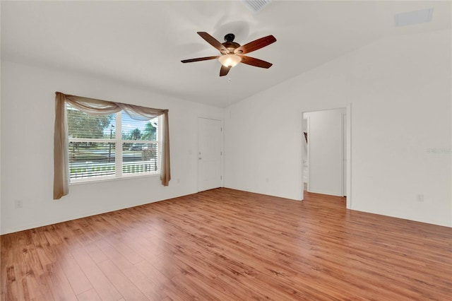 unfurnished room featuring light wood finished floors, ceiling fan, visible vents, and vaulted ceiling