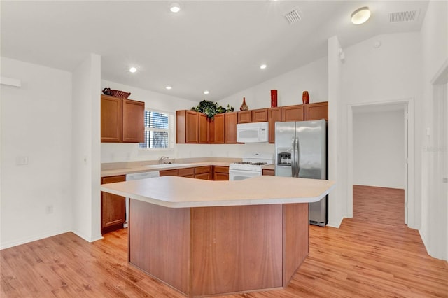 kitchen with light wood finished floors, lofted ceiling, light countertops, visible vents, and white appliances