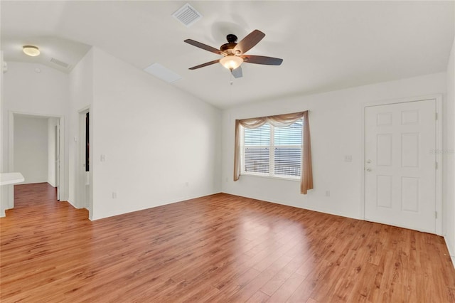 empty room with a ceiling fan, visible vents, vaulted ceiling, and light wood-style flooring