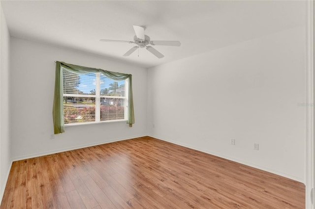 empty room with ceiling fan, baseboards, and wood finished floors