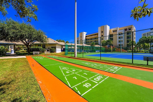 view of community featuring shuffleboard, a lawn, and fence