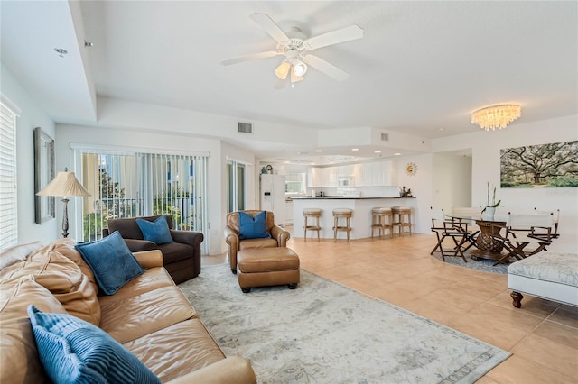 living area with ceiling fan with notable chandelier, visible vents, and light tile patterned floors