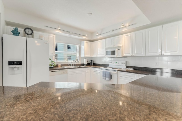 kitchen featuring white appliances, white cabinetry, dark stone counters, and a sink