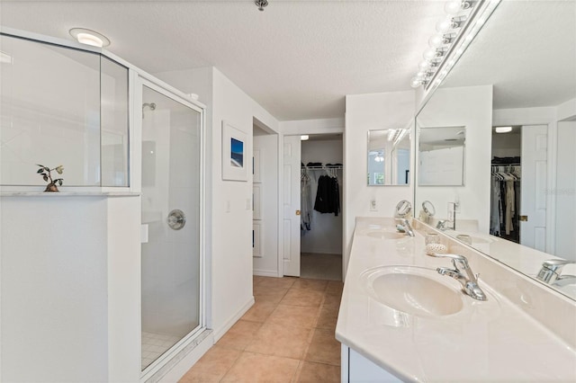 bathroom with a stall shower, a sink, and tile patterned floors