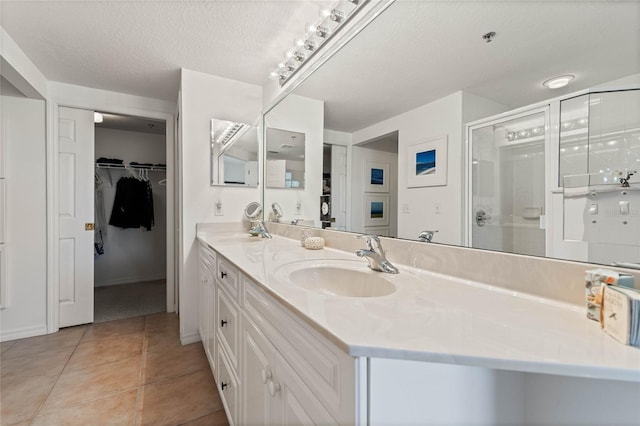 bathroom featuring a stall shower, a textured ceiling, a sink, and tile patterned floors