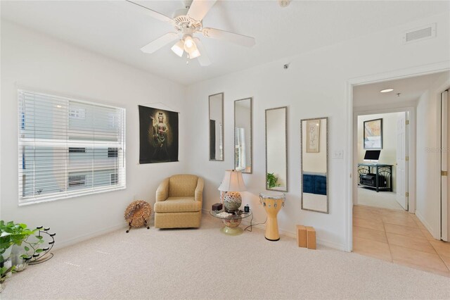 sitting room featuring light colored carpet, visible vents, light tile patterned flooring, ceiling fan, and baseboards