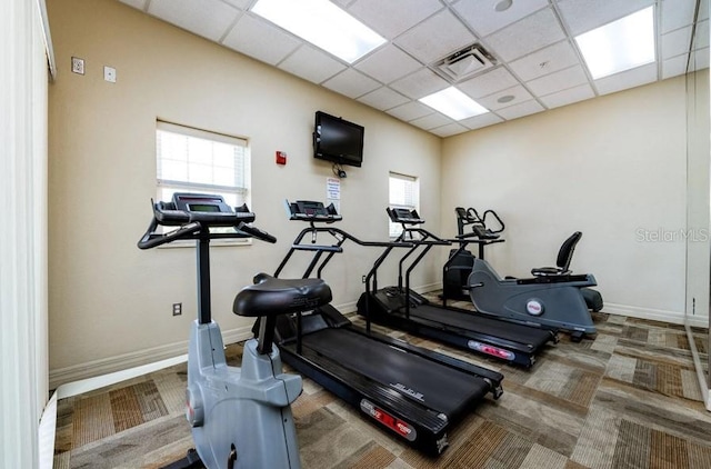 exercise room with a wealth of natural light, visible vents, and a paneled ceiling