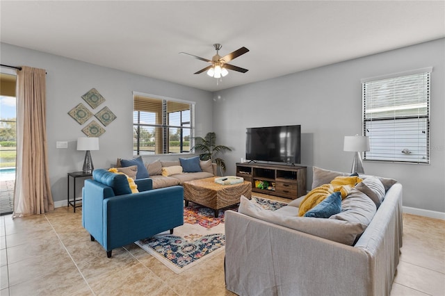 living area with light tile patterned flooring, ceiling fan, and baseboards