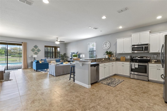 kitchen featuring open floor plan, a peninsula, stainless steel appliances, and visible vents