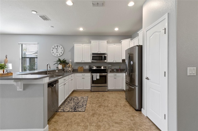 kitchen with a sink, a peninsula, visible vents, and stainless steel appliances