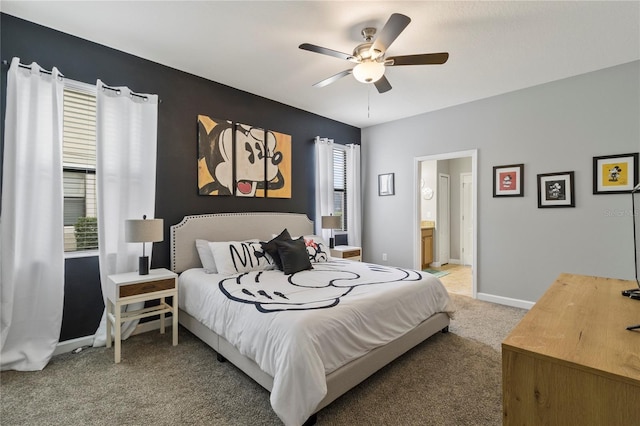 bedroom with connected bathroom, light colored carpet, baseboards, and ceiling fan