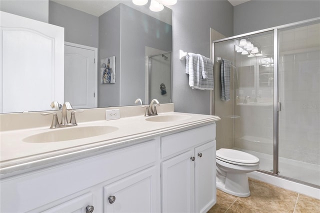 bathroom featuring a shower stall, toilet, double vanity, and a sink