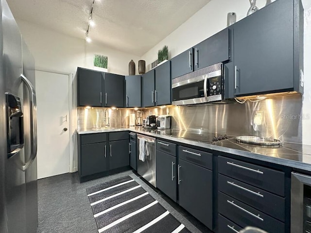 kitchen with stainless steel countertops, backsplash, appliances with stainless steel finishes, a sink, and beverage cooler