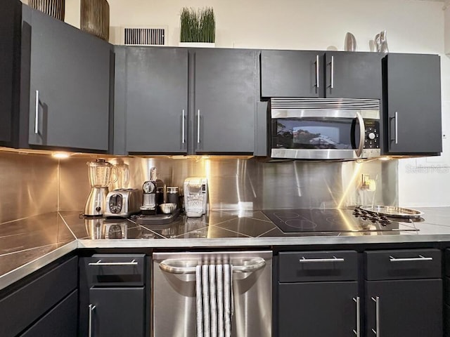 kitchen featuring stainless steel counters, stainless steel microwave, black electric cooktop, and backsplash