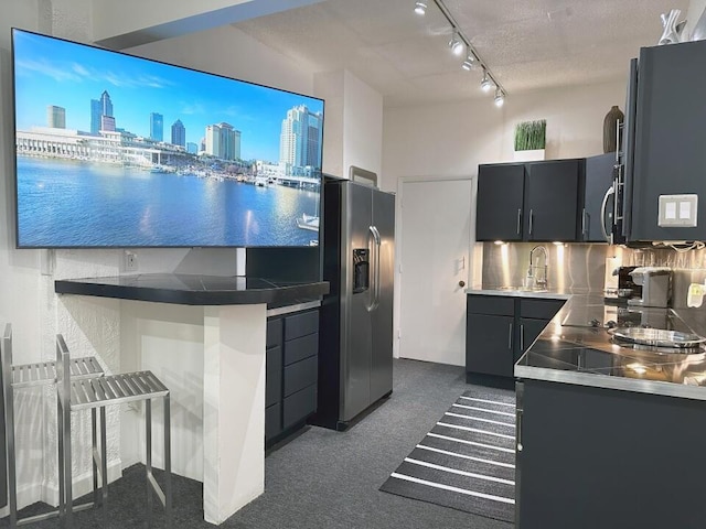 kitchen with tasteful backsplash, stainless steel counters, appliances with stainless steel finishes, a sink, and dark cabinets