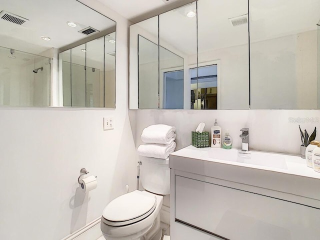 bathroom featuring toilet, vanity, and visible vents