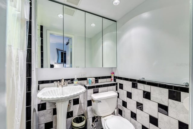 full bathroom with visible vents, toilet, and tile walls