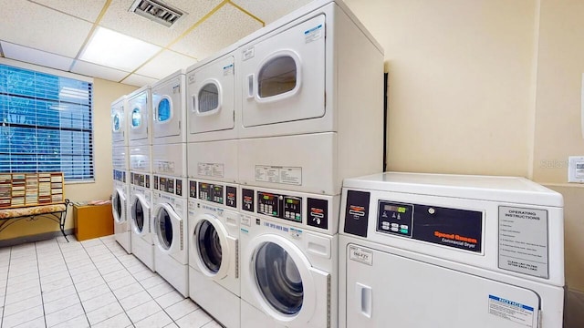 shared laundry area with light tile patterned floors, washing machine and dryer, visible vents, and stacked washer and clothes dryer