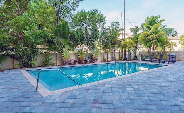 view of swimming pool featuring a fenced in pool, a patio area, a fenced backyard, and area for grilling