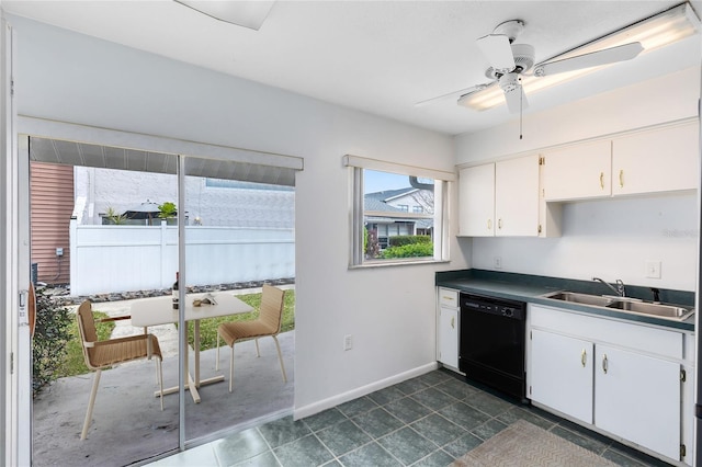 kitchen with baseboards, dishwasher, dark countertops, white cabinetry, and a sink