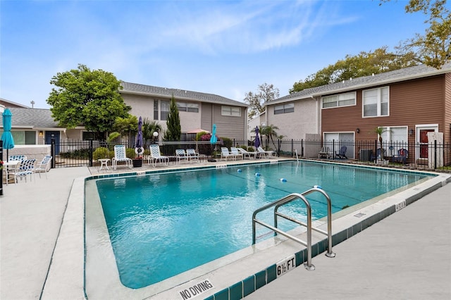 pool with a patio area and fence