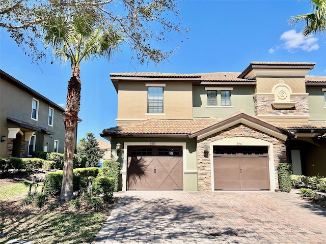 view of front of home featuring stone siding, decorative driveway, a tiled roof, and stucco siding