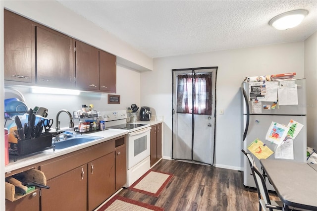 kitchen with electric stove, light countertops, dark wood-type flooring, freestanding refrigerator, and a sink