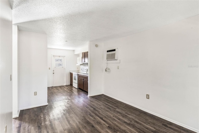 empty room featuring an AC wall unit, baseboards, a textured ceiling, and dark wood-style flooring