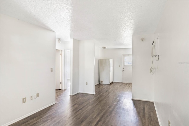 spare room with dark wood-style floors, a textured ceiling, and baseboards