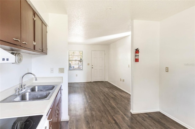 kitchen featuring dark wood-style flooring, light countertops, a sink, a textured ceiling, and black electric cooktop