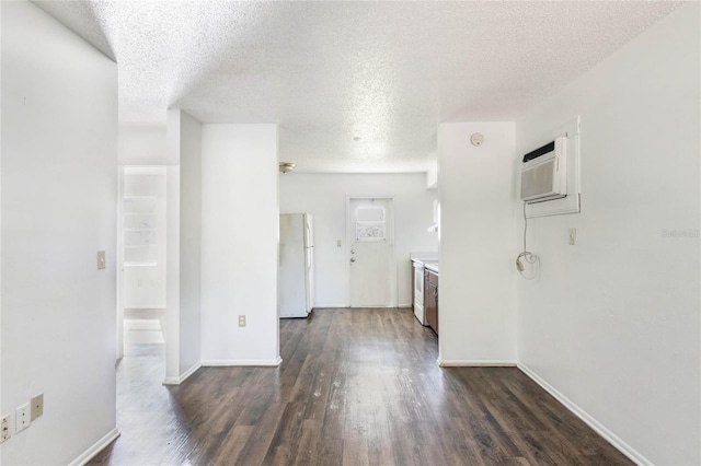 spare room with a textured ceiling, dark wood-style flooring, and baseboards