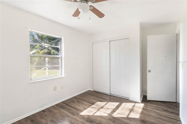 unfurnished bedroom with a closet, a textured ceiling, baseboards, and wood finished floors