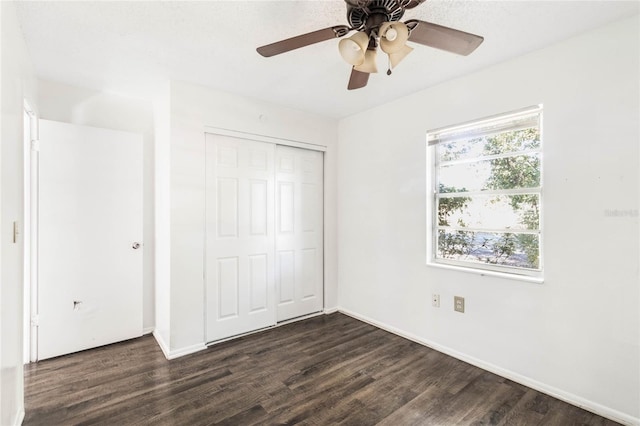 unfurnished bedroom featuring ceiling fan, dark wood-style flooring, a closet, and baseboards