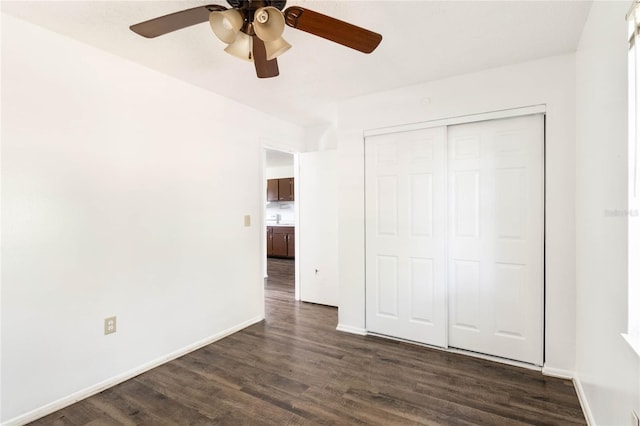 unfurnished bedroom with dark wood-style floors, a closet, ceiling fan, and baseboards