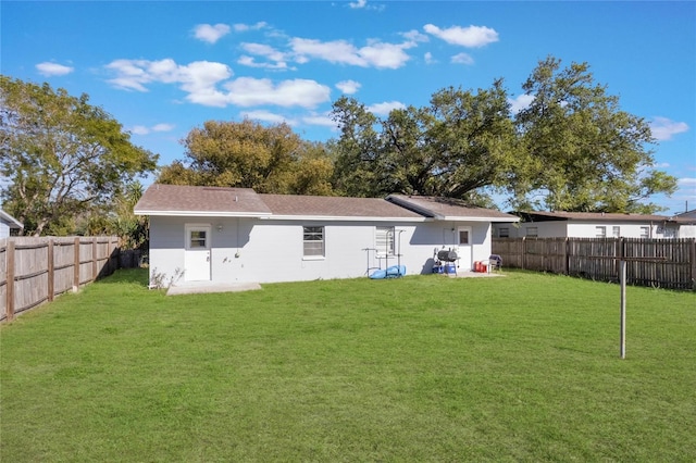 rear view of house with a yard and a fenced backyard