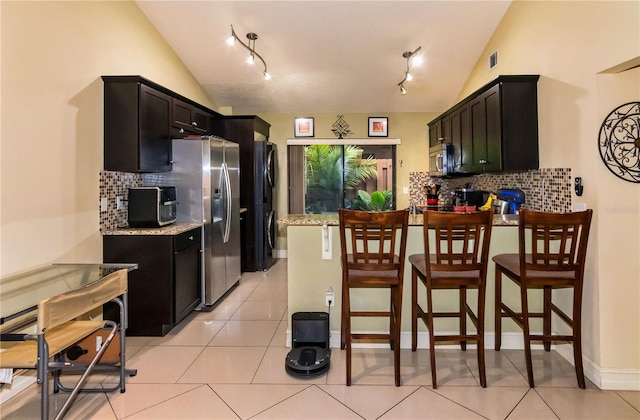 kitchen with visible vents, lofted ceiling, appliances with stainless steel finishes, a peninsula, and light tile patterned flooring